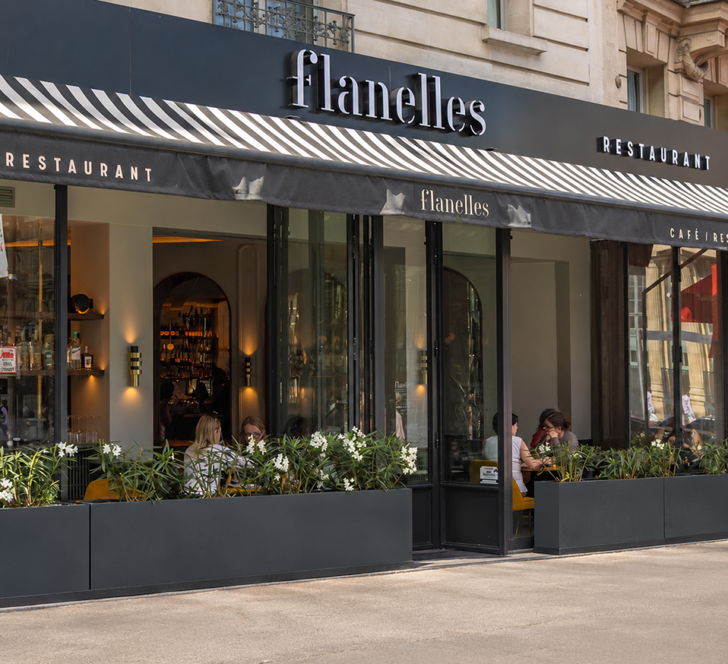Façade du Flanelles Café à Paris 10e, situé face à la Gare du Nord, avec ses grandes baies vitrées et son enseigne Flanelles.